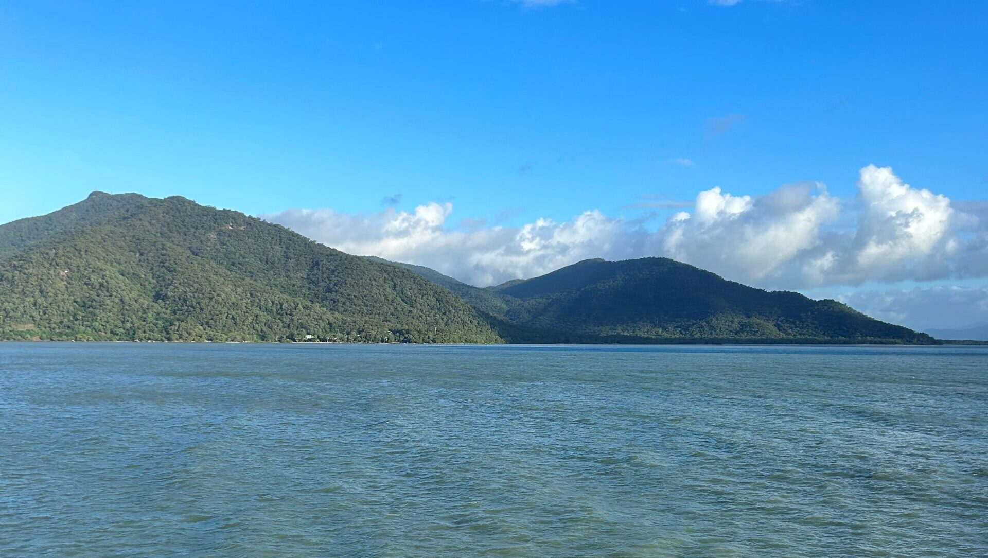 Photo of Fitzroy Island in a calm ocean with cloudy and blue skies.