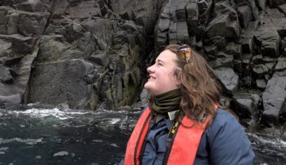 Student, Kennedy Fast, on one of the Zodiac day excursions with rocky cliff face behind